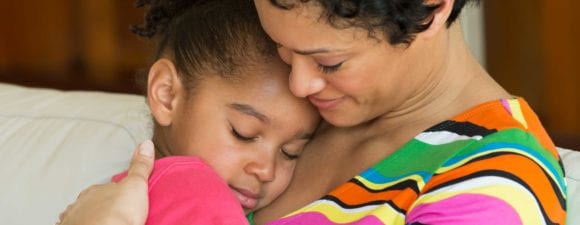 一名黑人妇女抱着她年幼的女儿，帮助其他人了解儿童的心理健康意识