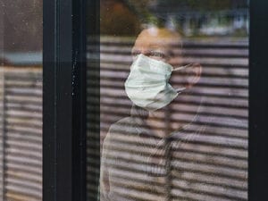 一名戴着口罩的男子望着窗外