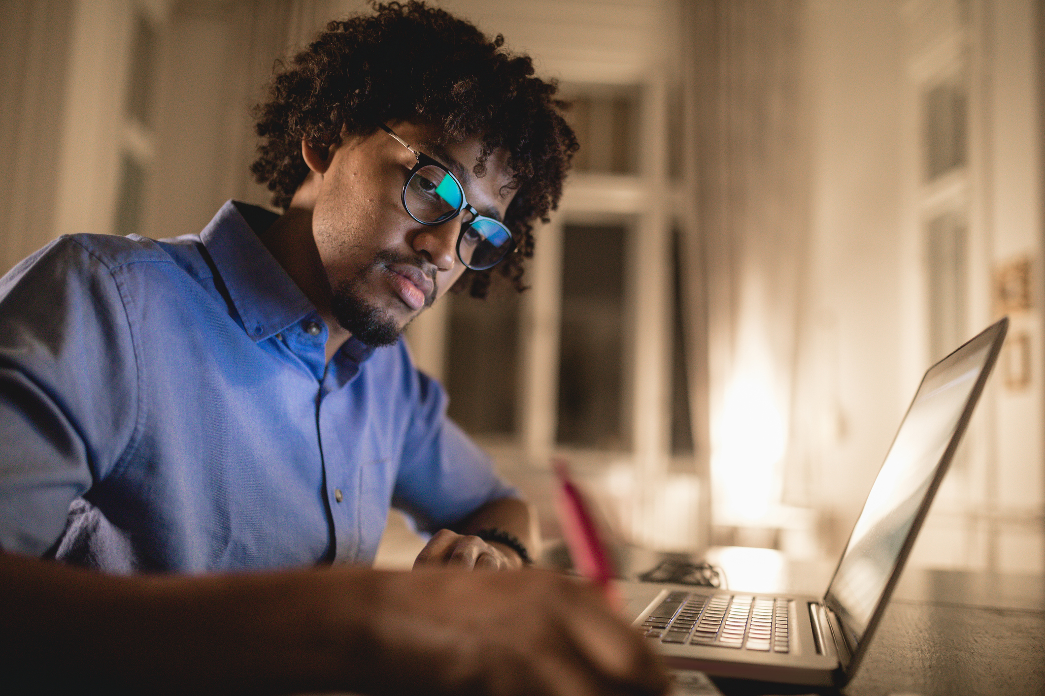 年轻而坚定的黑人学生，在笔记本电脑的帮助下，晚上在家里学习。